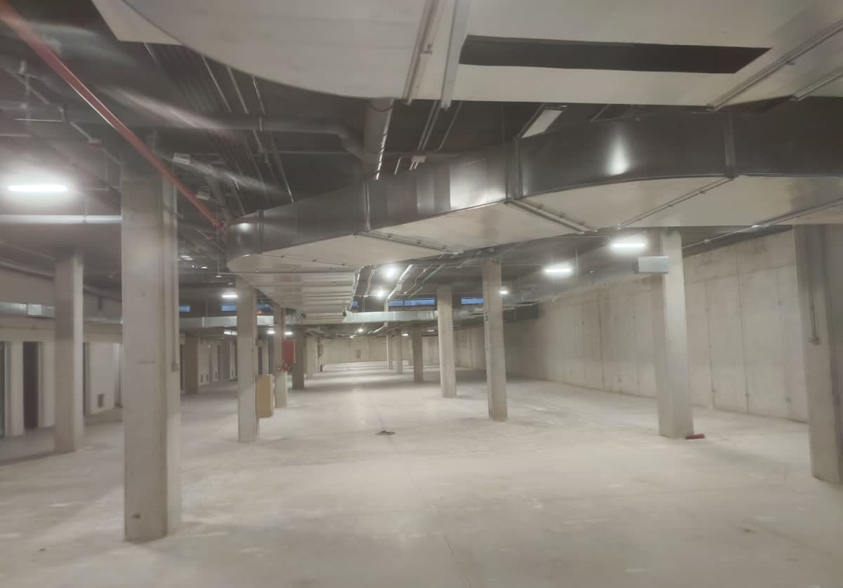 Sótano de un edificio en obra con bandejas de cableado y alumbrado provisional